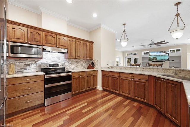 kitchen with ceiling fan, a sink, under cabinet range hood, appliances with stainless steel finishes, and brown cabinets