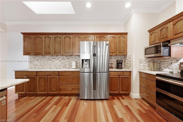 kitchen featuring ornamental molding, stainless steel appliances, a skylight, brown cabinetry, and light wood finished floors