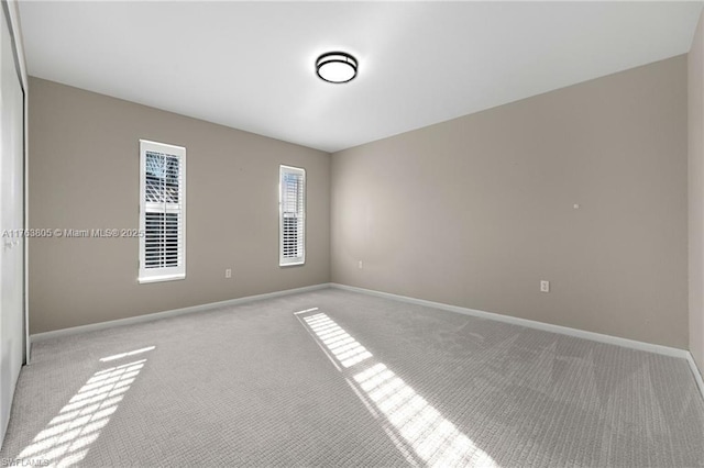 carpeted empty room featuring baseboards