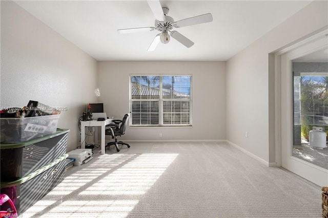 carpeted office space featuring baseboards and ceiling fan