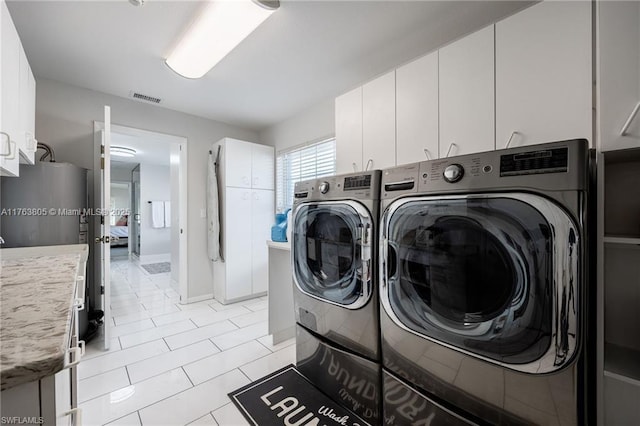 laundry area with cabinet space, visible vents, washing machine and dryer, and light tile patterned floors