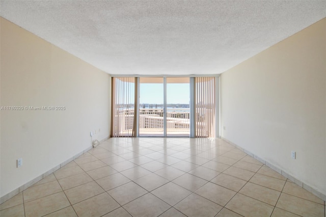 empty room featuring a wall of windows, a textured ceiling, and light tile patterned floors