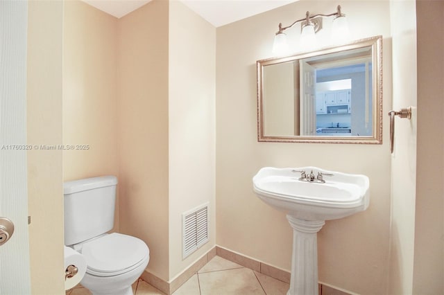 half bathroom with tile patterned flooring, toilet, baseboards, and visible vents