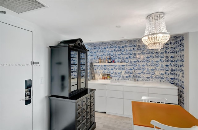 interior space with visible vents, open shelves, light countertops, white cabinetry, and a chandelier