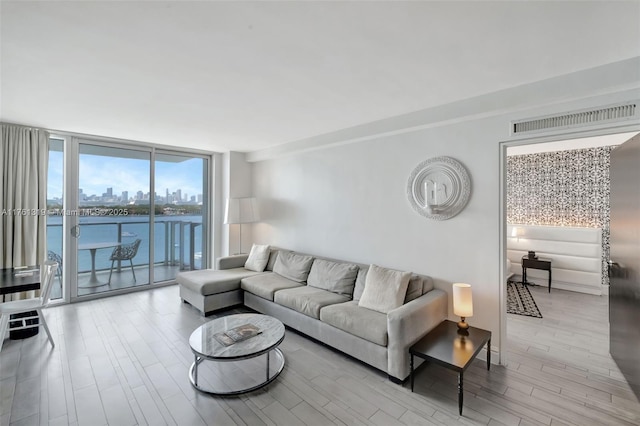 living room featuring expansive windows, a view of city, visible vents, and wood finished floors