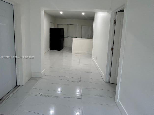 corridor with baseboards and marble finish floor