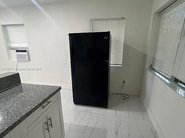 kitchen with cooling unit, dark stone counters, freestanding refrigerator, white cabinets, and marble finish floor