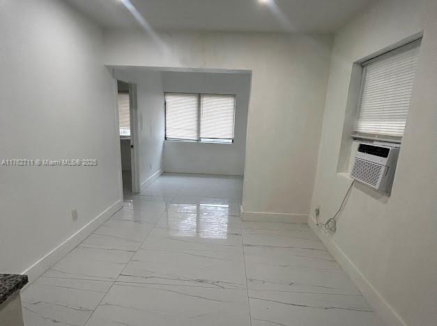 corridor featuring marble finish floor, cooling unit, and baseboards