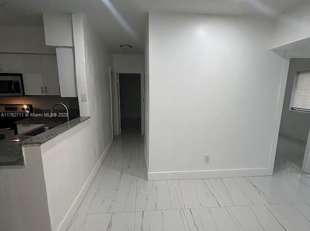 kitchen featuring dark stone counters, baseboards, marble finish floor, and stainless steel appliances