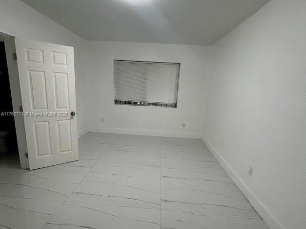 unfurnished room featuring marble finish floor and baseboards