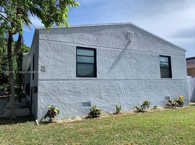 view of property exterior with crawl space, stucco siding, and a yard