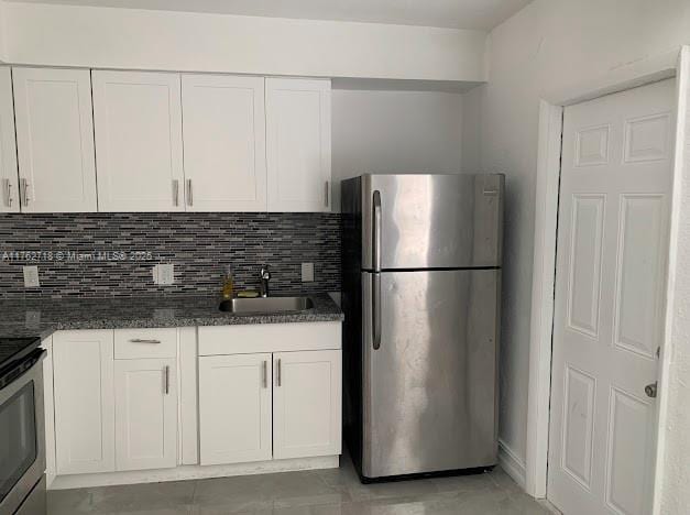 kitchen featuring tasteful backsplash, white cabinets, stainless steel appliances, and a sink