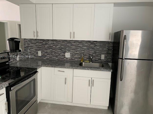 kitchen with a sink, decorative backsplash, appliances with stainless steel finishes, and white cabinetry