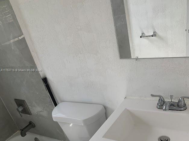 bathroom with a washtub, toilet, and a sink