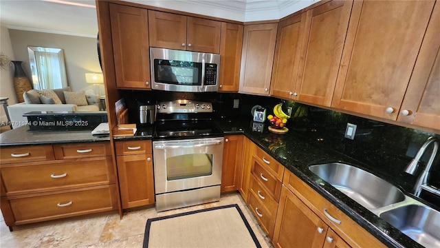 kitchen with a sink, appliances with stainless steel finishes, crown molding, brown cabinets, and backsplash