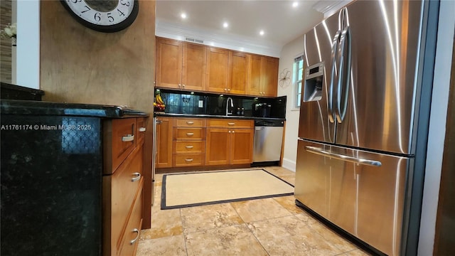 kitchen with decorative backsplash, brown cabinets, appliances with stainless steel finishes, and crown molding