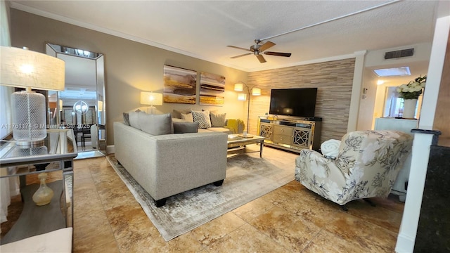 living area featuring an accent wall, crown molding, a ceiling fan, and visible vents