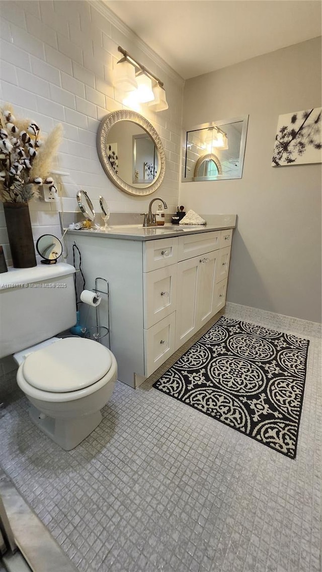 bathroom with toilet, tile walls, vanity, and tile patterned flooring