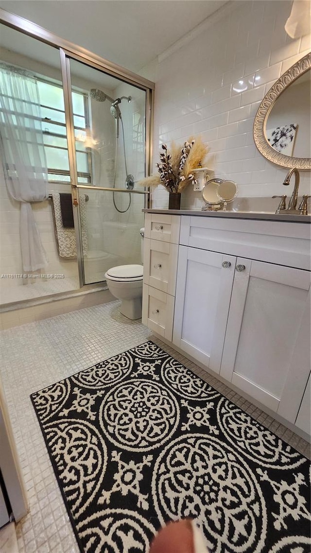 full bathroom with toilet, tile walls, a shower stall, tile patterned flooring, and vanity