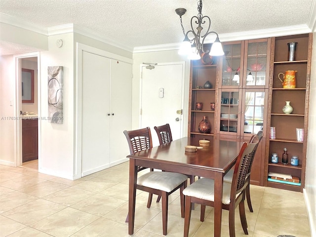 dining space with a textured ceiling, ornamental molding, light tile patterned flooring, and a chandelier