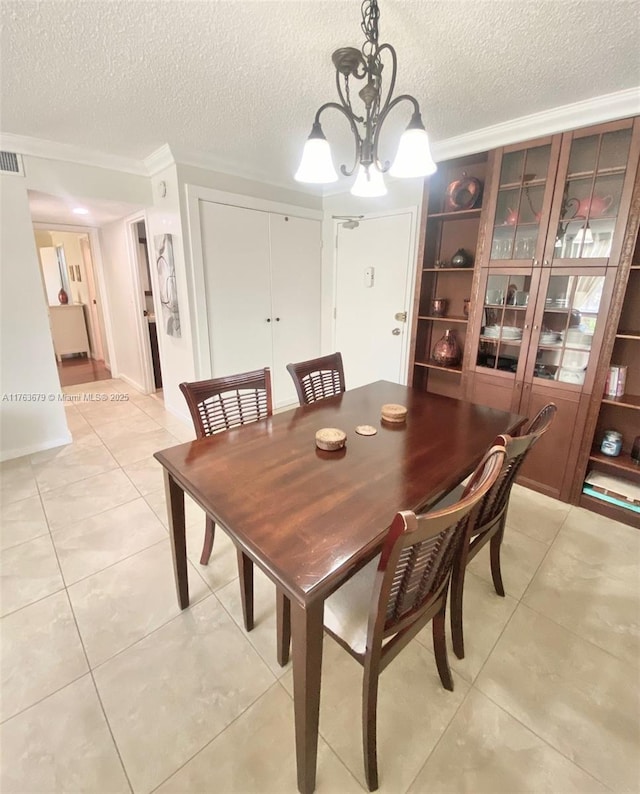 dining area with visible vents, a notable chandelier, ornamental molding, a textured ceiling, and light tile patterned floors