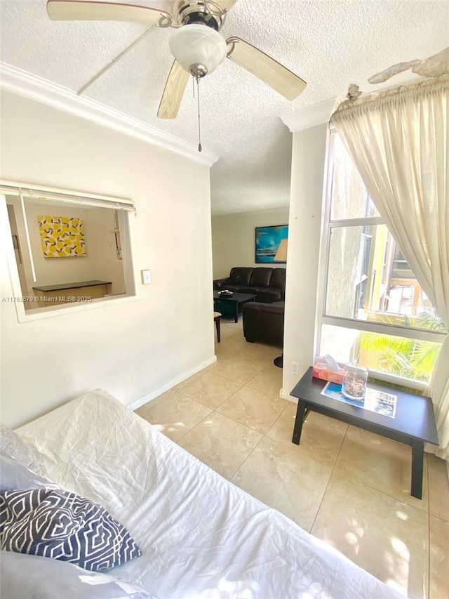 living room featuring tile patterned flooring, baseboards, ornamental molding, a textured ceiling, and a ceiling fan