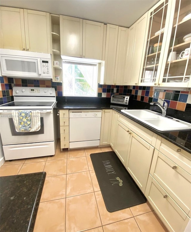 kitchen featuring light tile patterned floors, white appliances, backsplash, and a sink