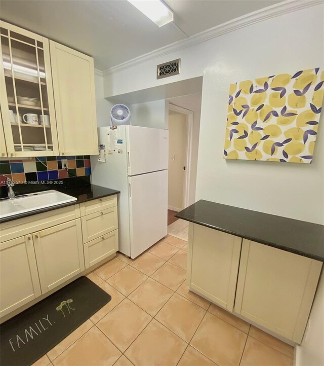 kitchen featuring crown molding, light tile patterned flooring, a sink, and freestanding refrigerator