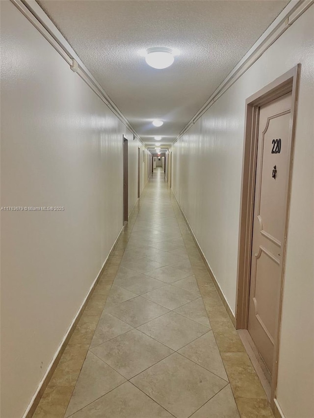 hallway featuring a textured ceiling, light tile patterned floors, and ornamental molding