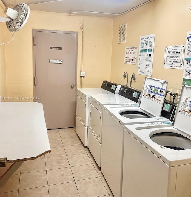 community laundry room featuring light tile patterned floors, visible vents, and washing machine and dryer
