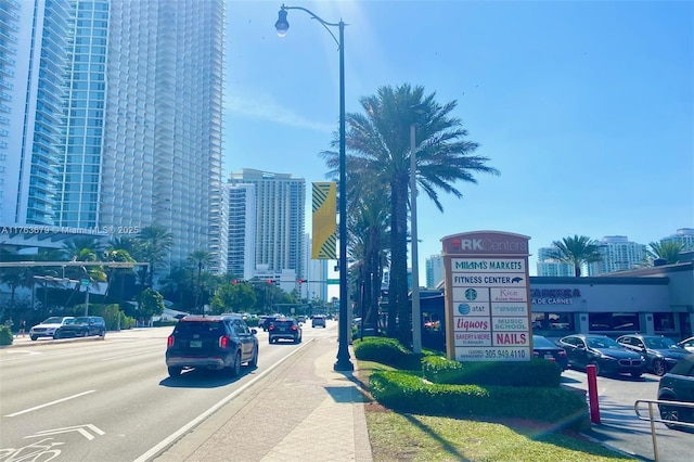 view of street with curbs, street lighting, sidewalks, a city view, and traffic lights