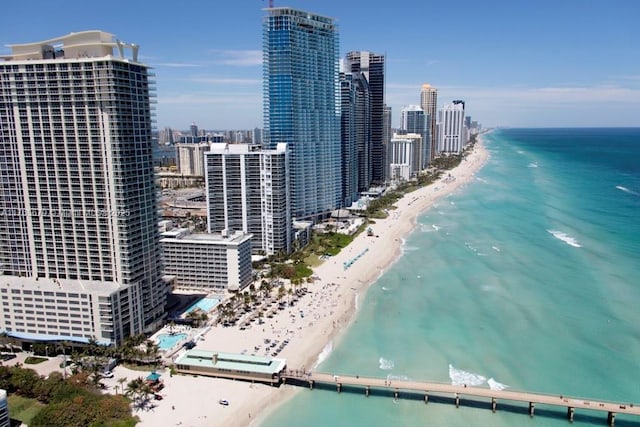 drone / aerial view featuring a view of city, a water view, and a beach view