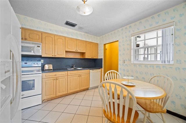 kitchen with dark countertops, visible vents, wallpapered walls, white appliances, and a sink