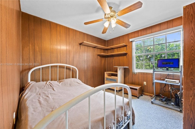 carpeted bedroom featuring wooden walls and ceiling fan