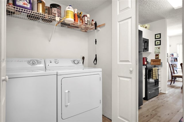 laundry room with light wood-style flooring, a textured ceiling, washing machine and dryer, and laundry area