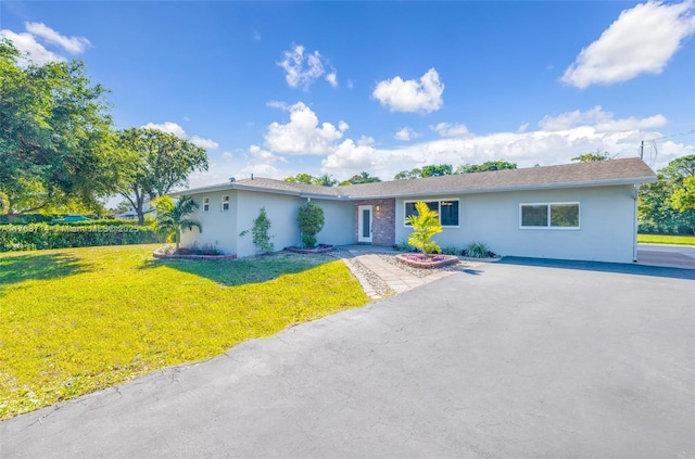 ranch-style house with stucco siding, driveway, and a front lawn