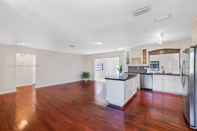 kitchen with dark countertops, visible vents, open floor plan, stainless steel appliances, and a sink