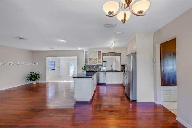 kitchen featuring dark countertops, visible vents, stainless steel appliances, and glass insert cabinets