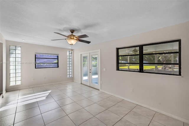 spare room with a ceiling fan, a textured ceiling, french doors, light tile patterned floors, and baseboards