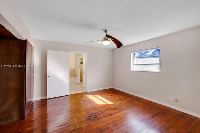 unfurnished bedroom with ceiling fan, connected bathroom, baseboards, and hardwood / wood-style floors