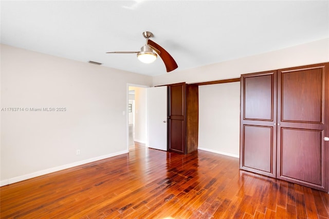 unfurnished bedroom featuring dark wood finished floors, visible vents, a ceiling fan, and baseboards