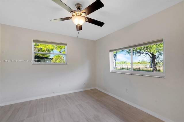 empty room with plenty of natural light, a ceiling fan, and baseboards