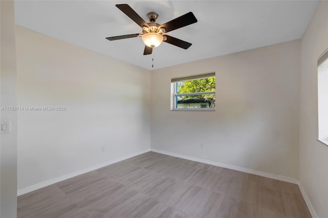 empty room with ceiling fan and baseboards