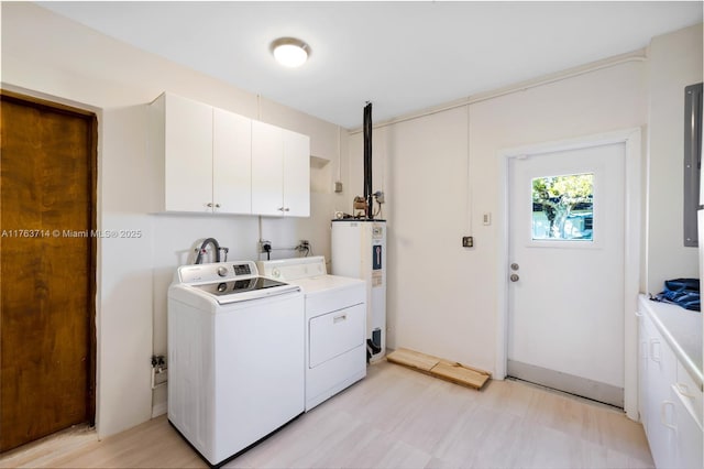 laundry room with water heater, washing machine and dryer, and cabinet space