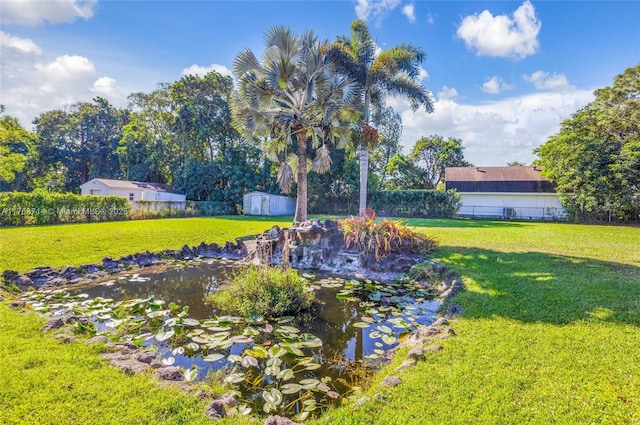 view of yard with an outbuilding, a garden pond, a storage shed, and fence