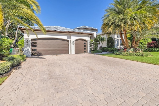 view of front of home featuring decorative driveway, stucco siding, an attached garage, and a tiled roof