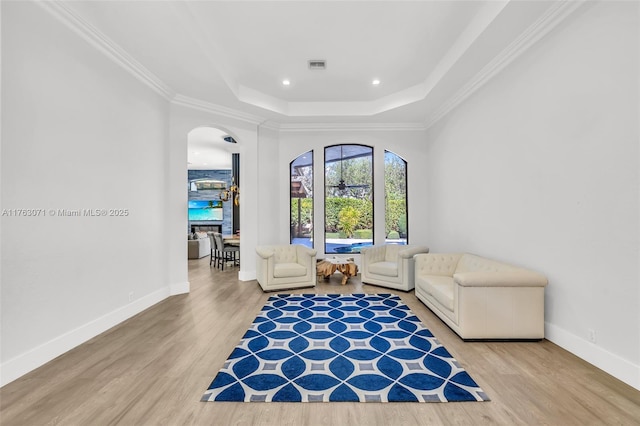 living area featuring visible vents, arched walkways, a raised ceiling, and wood finished floors