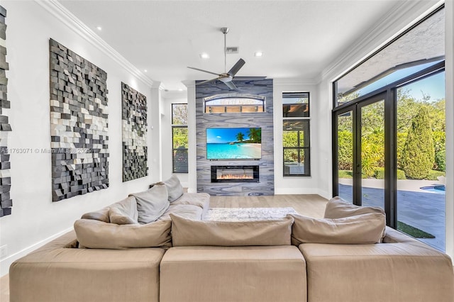 living area with baseboards, a ceiling fan, ornamental molding, and a fireplace