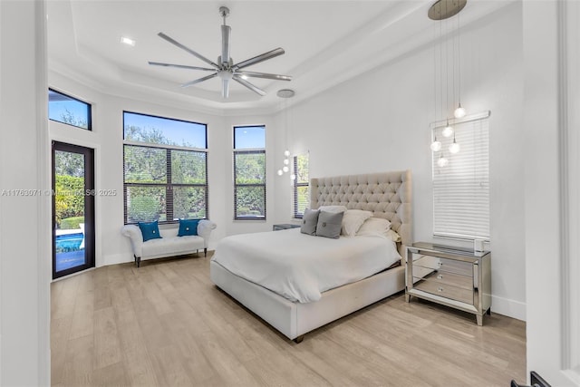 bedroom featuring a tray ceiling, access to outside, baseboards, and light wood finished floors