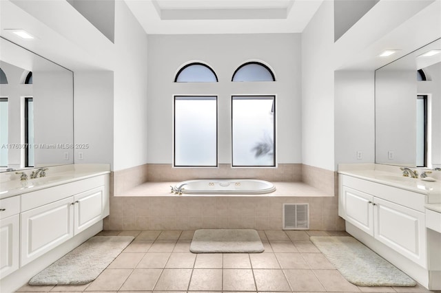 full bath featuring tile patterned flooring, visible vents, a garden tub, two vanities, and a sink